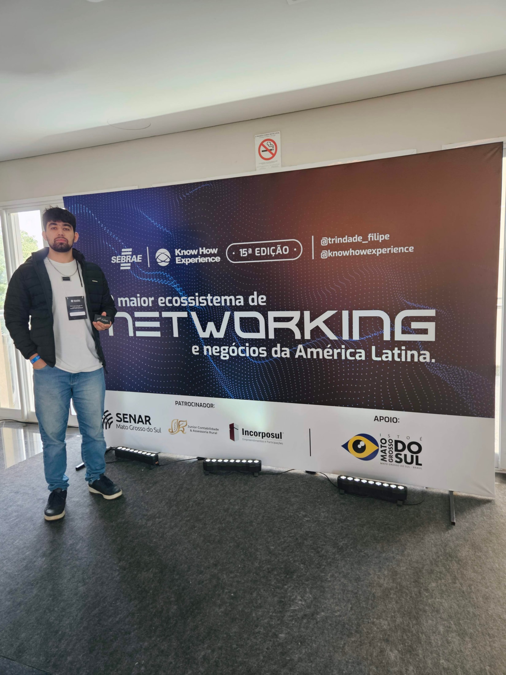 Felipe ao lado do painel do Know How Experience